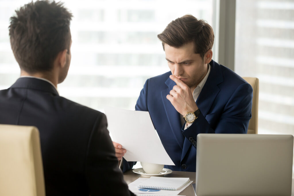 A immigration officer reviewing a document during an interview, appearing deep in thought while sitting across from the applicant.